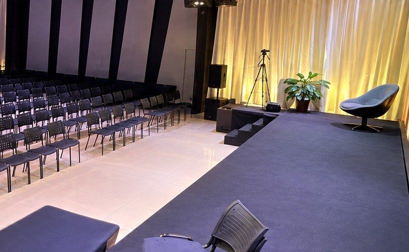 Palco da Vertix Hall vazio, com poltrona ao centro e cadeiras posicionadas à frente