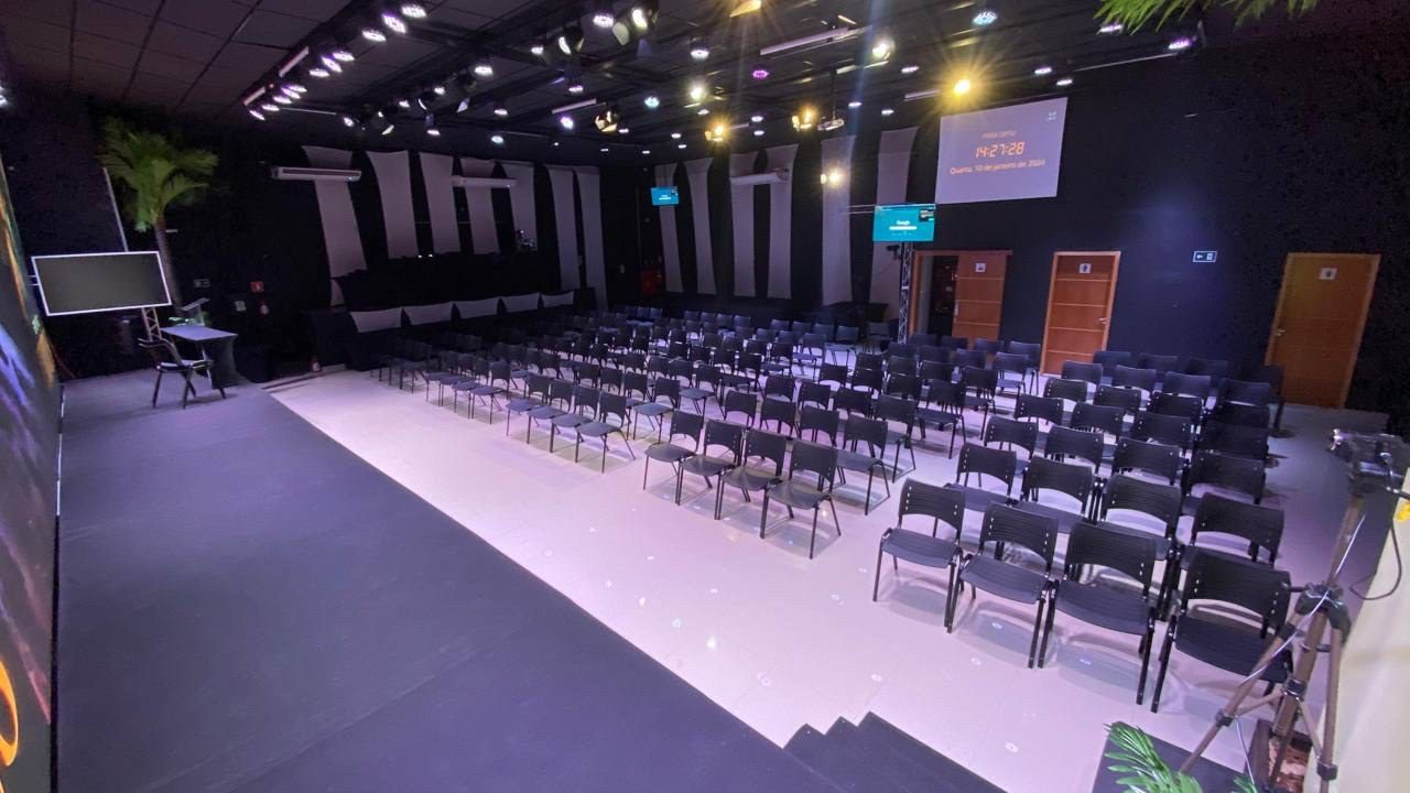 Espaço montado em formato auditório, com fileiras de cadeiras voltadas para o palco.