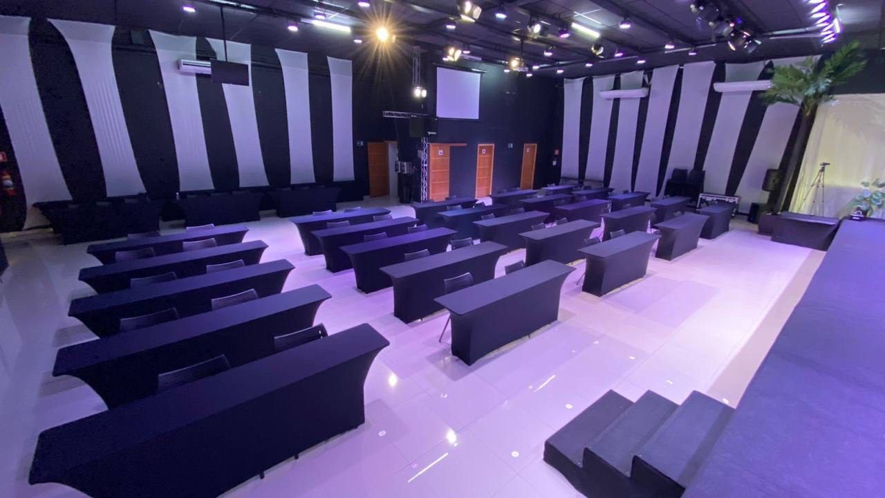 Salão montado em formato escolar voltado ao palco