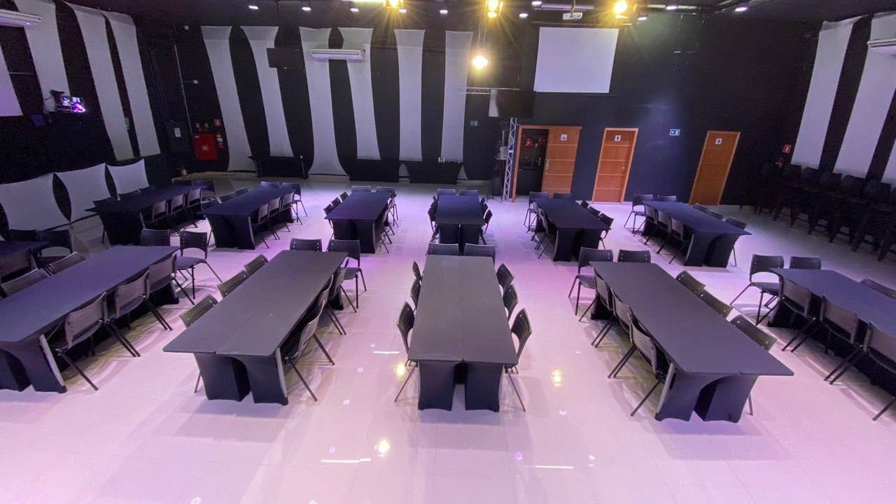 Espaço montado em formato ilhas, com mesas agrupadas de oito lugares para dinâmicas em grupo.